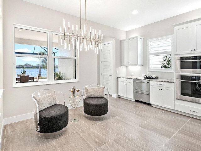 sitting room with a water view, light tile patterned floors, and a chandelier