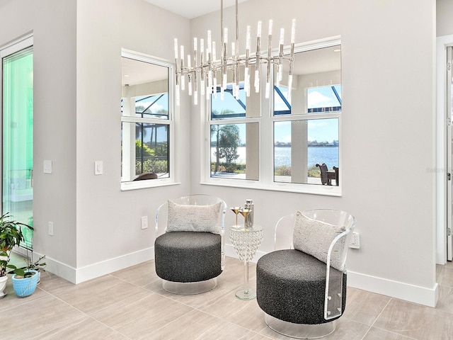 sitting room featuring tile patterned flooring, a water view, an inviting chandelier, and a healthy amount of sunlight