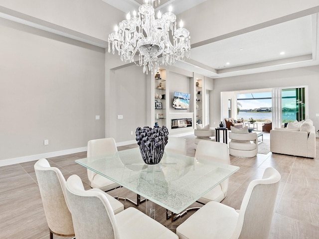 dining area featuring a tray ceiling, built in features, and a notable chandelier