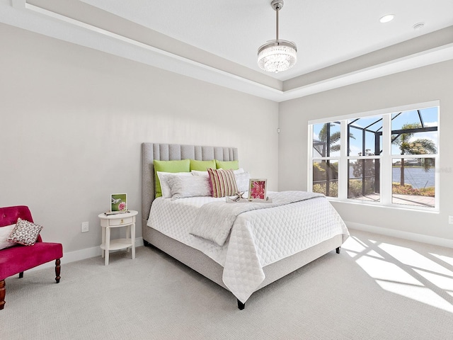 bedroom with carpet, an inviting chandelier, and a tray ceiling