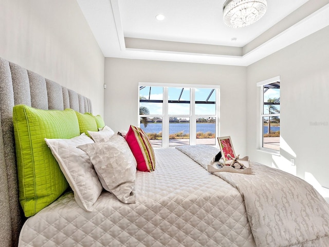 bedroom with a water view and a tray ceiling