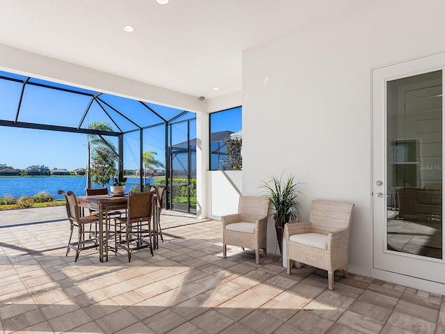 view of patio featuring glass enclosure and a water view