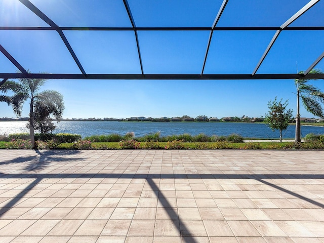 view of patio with a lanai and a water view