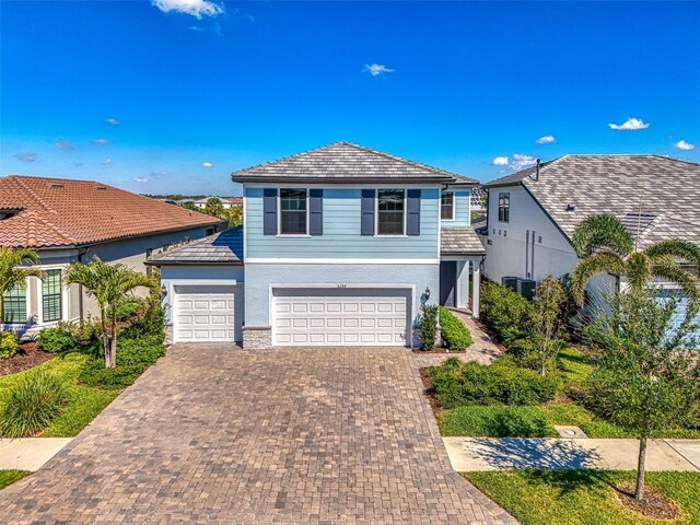 view of front of property with decorative driveway, an attached garage, and stucco siding