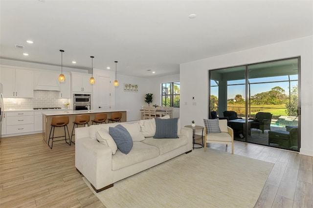 living area with light wood-type flooring, visible vents, and recessed lighting