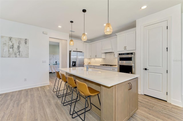 kitchen with backsplash, custom exhaust hood, stainless steel appliances, light wood-style floors, and a sink