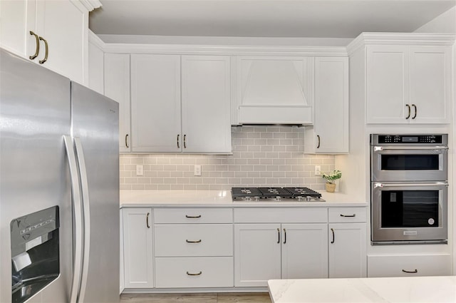 kitchen featuring light countertops, appliances with stainless steel finishes, white cabinetry, and tasteful backsplash