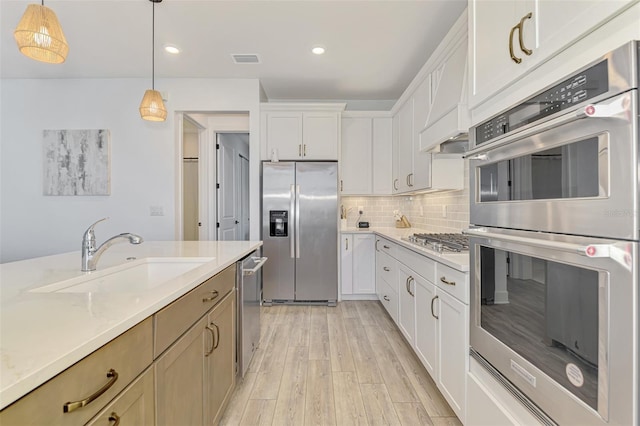 kitchen with a sink, visible vents, appliances with stainless steel finishes, light wood finished floors, and tasteful backsplash