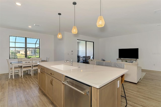 kitchen with light wood finished floors, open floor plan, a sink, an island with sink, and dishwasher