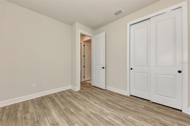 unfurnished bedroom with light wood finished floors, a closet, visible vents, and baseboards