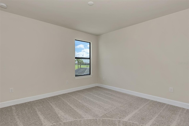 spare room featuring baseboards and light colored carpet