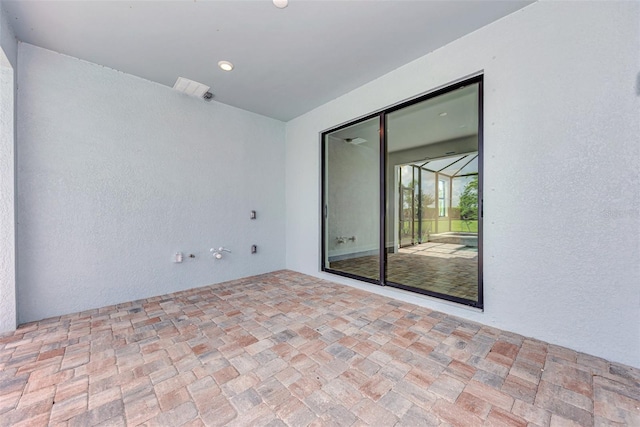 spare room with a textured wall, brick floor, a sunroom, and recessed lighting