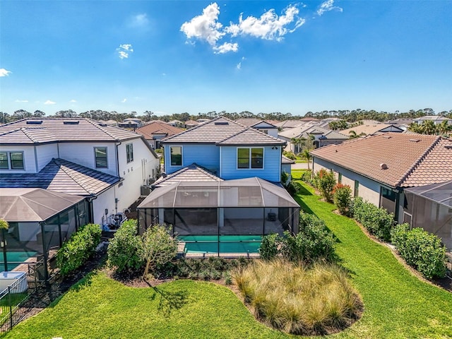 rear view of property featuring a lanai, a tile roof, a residential view, and a yard