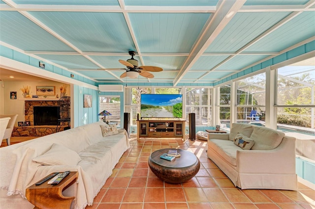 living room featuring tile patterned flooring, a stone fireplace, ceiling fan, and coffered ceiling