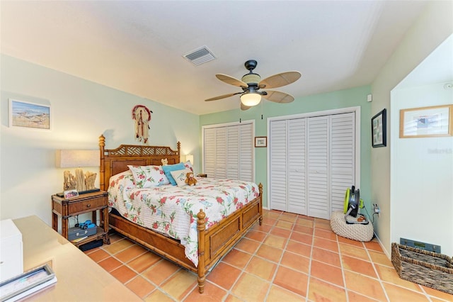 bedroom with light tile patterned floors, two closets, and ceiling fan