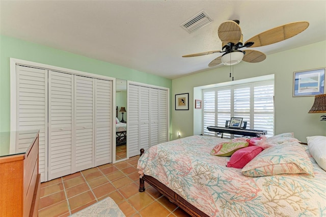 bedroom with ceiling fan, light tile patterned floors, and two closets