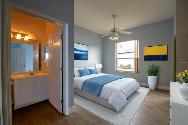 bedroom featuring hardwood / wood-style floors, ceiling fan, sink, and ensuite bath