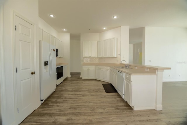 kitchen featuring white appliances, white cabinets, sink, tasteful backsplash, and kitchen peninsula