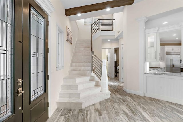 foyer entrance featuring beam ceiling, light hardwood / wood-style floors, and ornamental molding