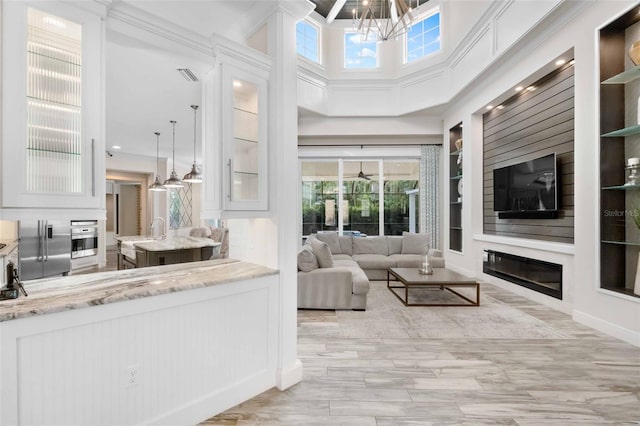 living room featuring built in shelves, sink, a high ceiling, and a notable chandelier