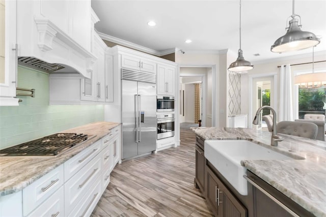 kitchen with white cabinets, stainless steel appliances, hanging light fixtures, and sink