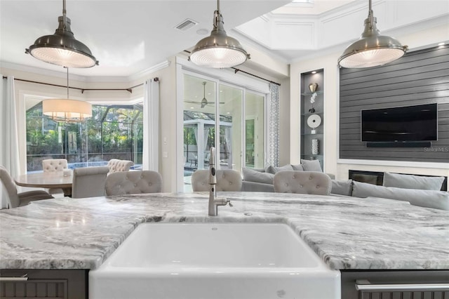 interior space with hanging light fixtures, plenty of natural light, ornamental molding, and sink