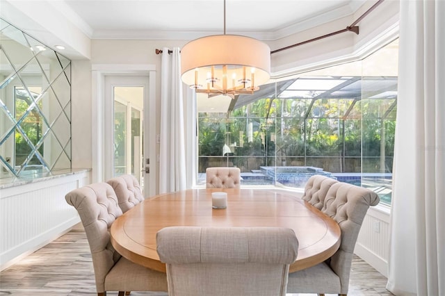 dining area featuring plenty of natural light, light wood-type flooring, ornamental molding, and an inviting chandelier