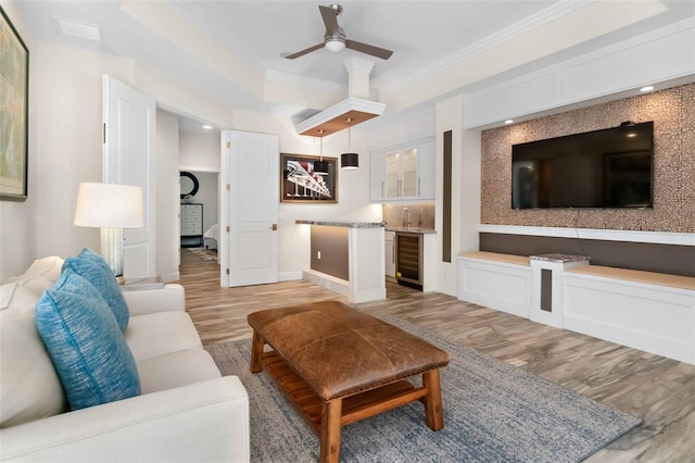 living room featuring wine cooler, ceiling fan, light hardwood / wood-style floors, and ornamental molding