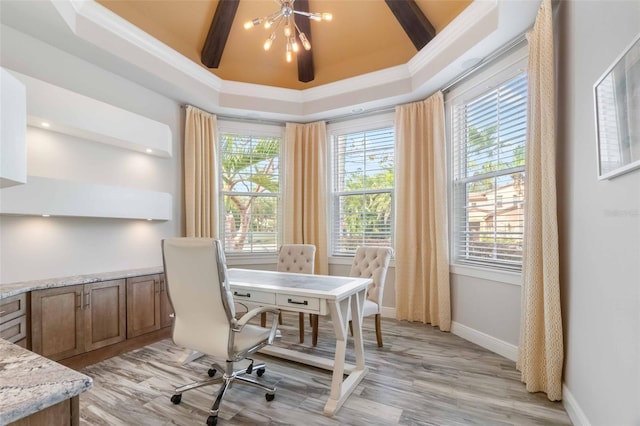 home office with a towering ceiling, light wood-type flooring, ornamental molding, a tray ceiling, and a chandelier