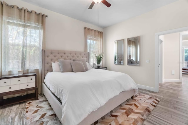 bedroom featuring ceiling fan, light hardwood / wood-style flooring, and multiple windows