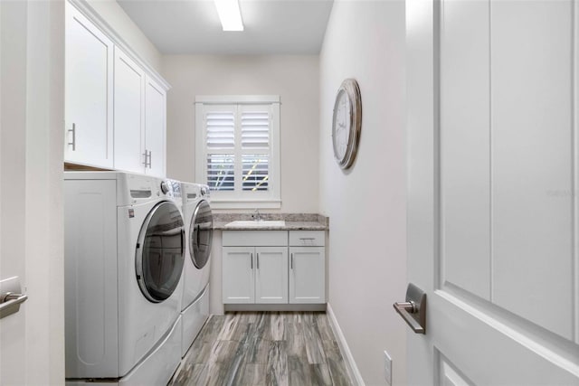 washroom featuring washing machine and dryer, sink, cabinets, and light wood-type flooring