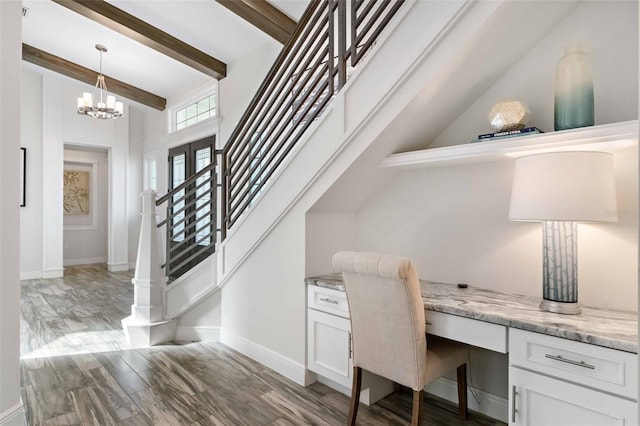 home office with vaulted ceiling with beams, built in desk, and an inviting chandelier