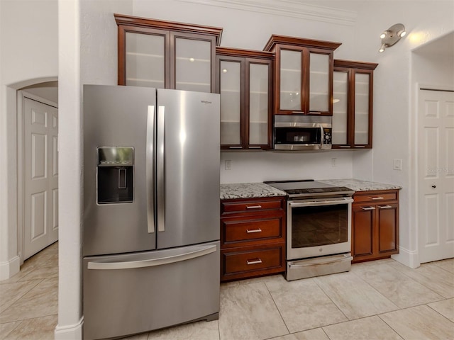 kitchen featuring light tile patterned floors, light stone countertops, crown molding, and stainless steel appliances