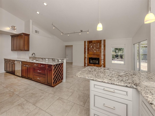 kitchen featuring light stone counters, hanging light fixtures, lofted ceiling, and a tiled fireplace