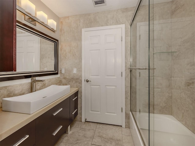 bathroom featuring enclosed tub / shower combo, tile patterned flooring, and vanity