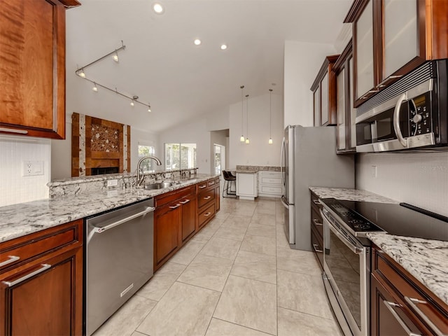 kitchen with vaulted ceiling, appliances with stainless steel finishes, light stone counters, and sink