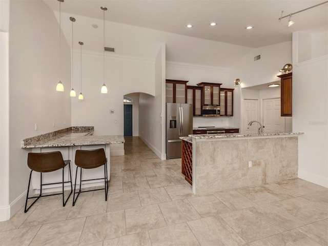 kitchen with kitchen peninsula, light stone counters, stainless steel appliances, and pendant lighting