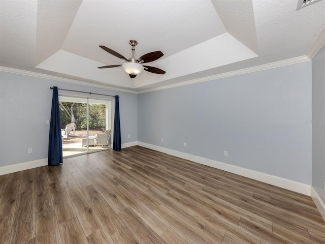 empty room with ceiling fan, hardwood / wood-style floors, crown molding, a tray ceiling, and a textured ceiling