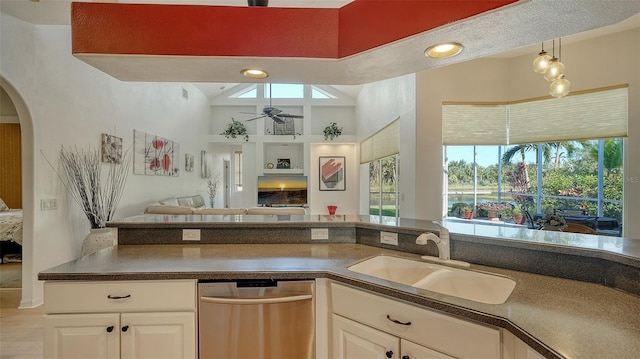 kitchen with ceiling fan, high vaulted ceiling, white cabinets, stainless steel dishwasher, and sink