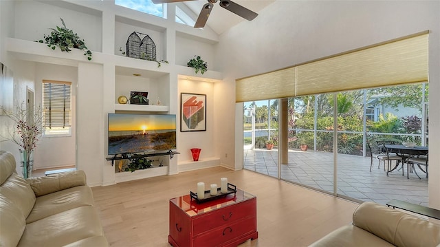 living room with high vaulted ceiling, ceiling fan, and light hardwood / wood-style floors