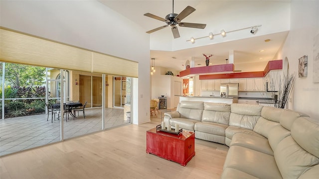 living room with a high ceiling, light wood-type flooring, and ceiling fan