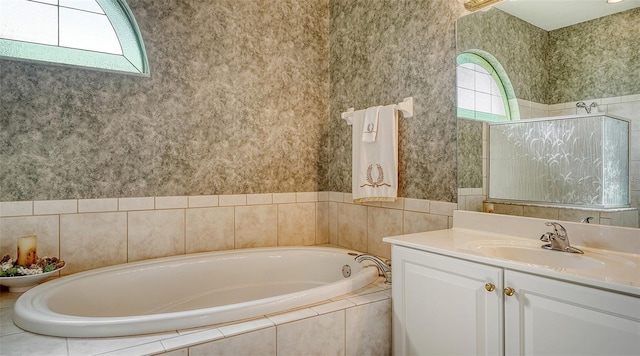 bathroom with tiled bath, a healthy amount of sunlight, and vanity