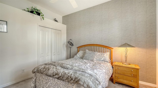 bedroom with ceiling fan, light colored carpet, and a closet