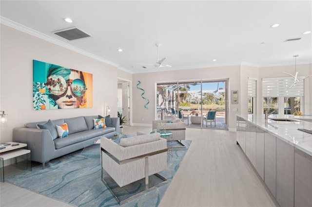 living room featuring sink, crown molding, and ceiling fan with notable chandelier