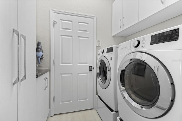 laundry area with separate washer and dryer and cabinets