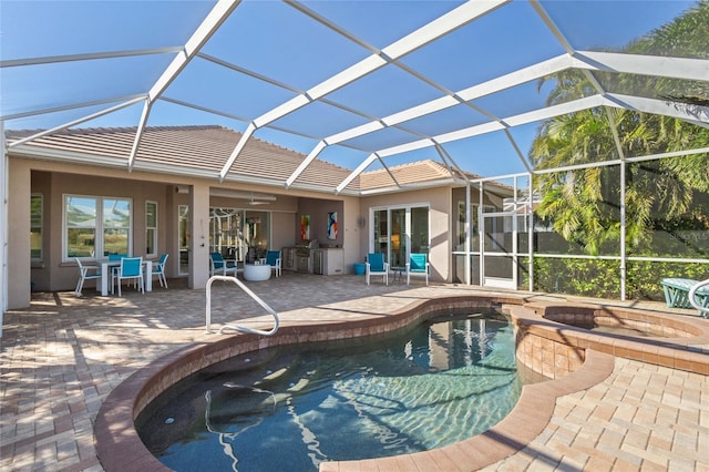 view of pool featuring exterior kitchen, ceiling fan, a patio area, and glass enclosure