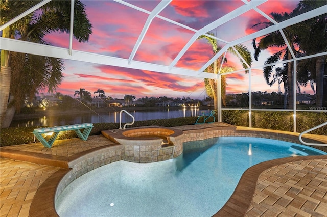 pool at dusk featuring a lanai, an in ground hot tub, a patio area, and a water view