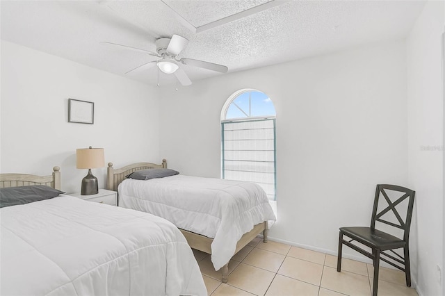 bedroom with ceiling fan, light tile patterned flooring, and a textured ceiling