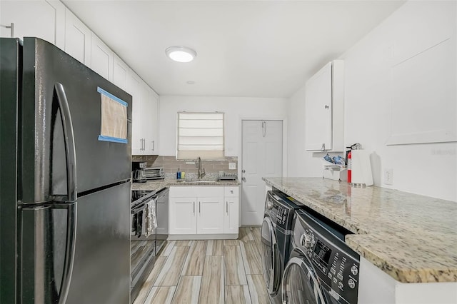 kitchen featuring black fridge, sink, light stone counters, white cabinetry, and washer / clothes dryer