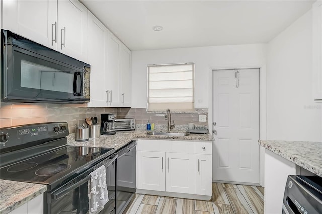 kitchen featuring sink, light stone counters, white cabinetry, and black appliances